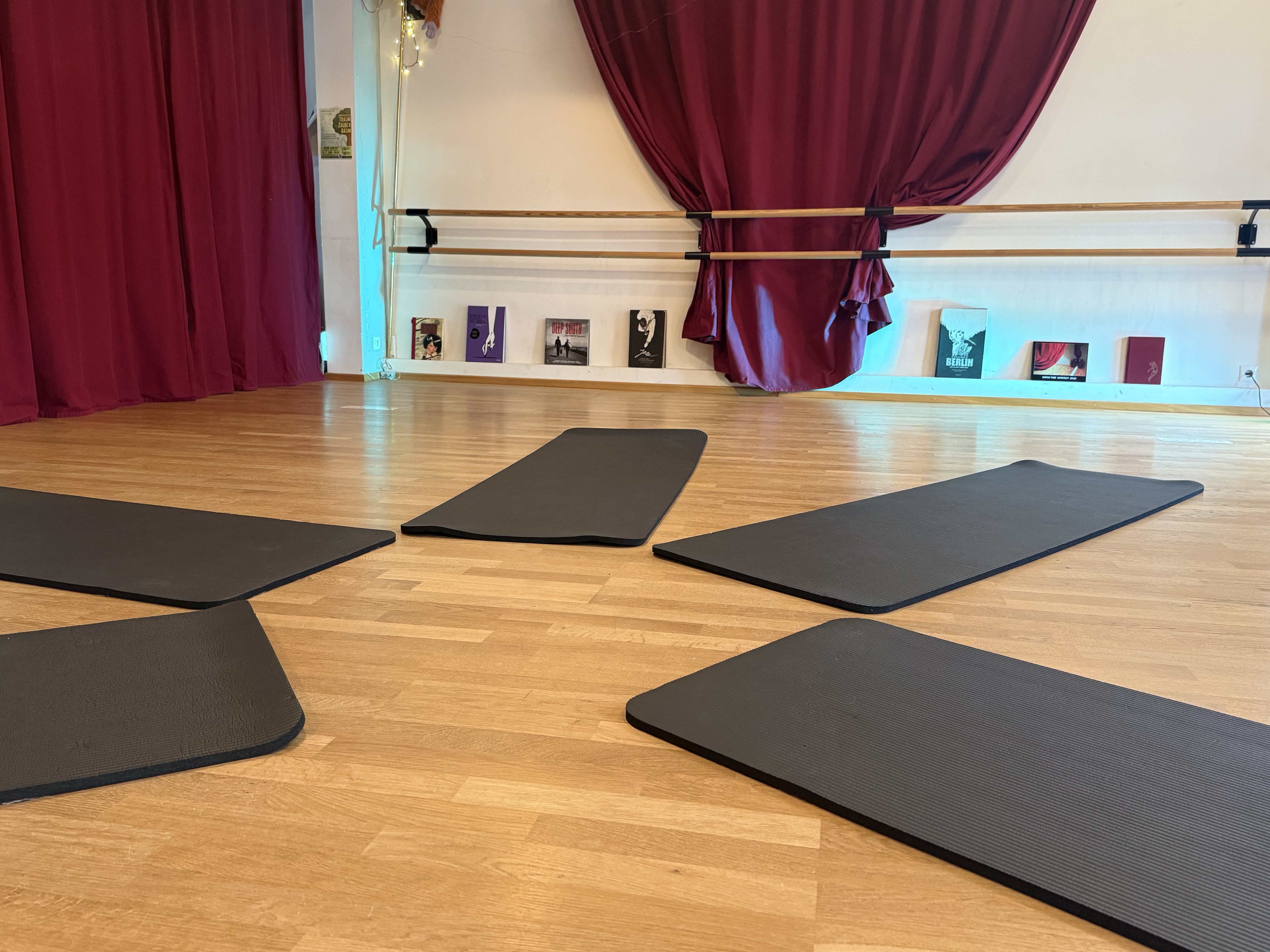 SWING TIME Tanzsaal mit Parkettboden, Yogamatten und roten Vorhängen